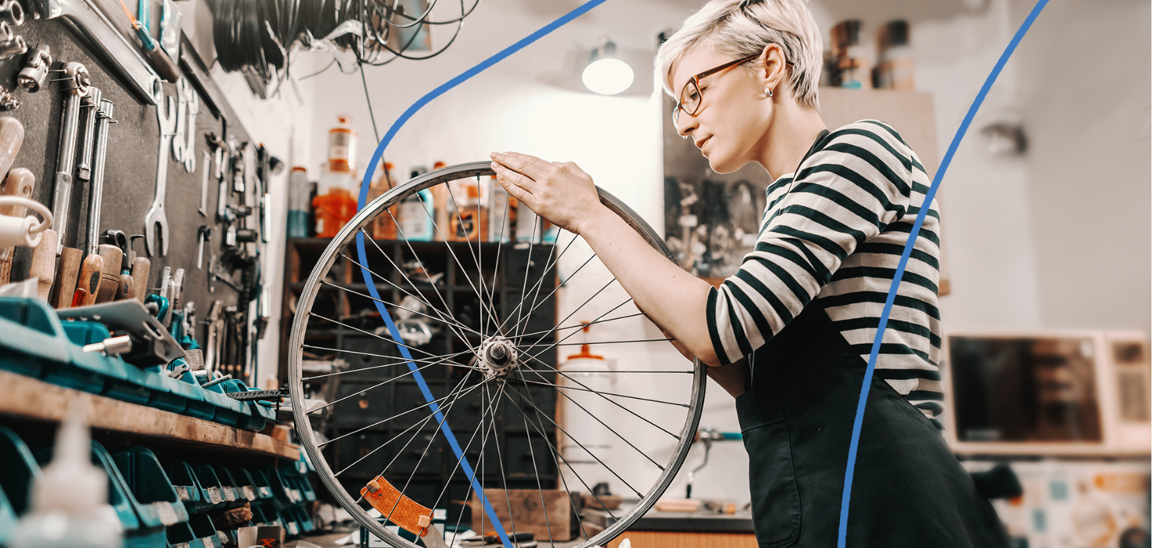 Bicycle shop owner truing a wheel in her repair shop, surrounded by tools and parts