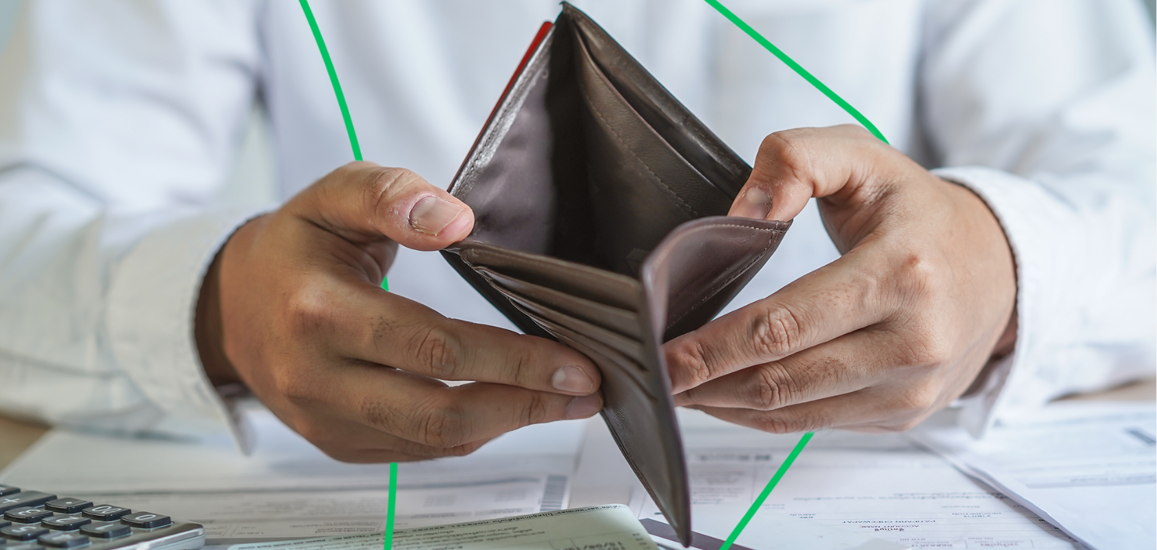 Two hands holding an empty brown wallet open over a pile of receipts and invoices
